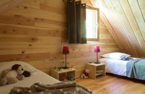 - une chambre avec des murs en bois et un lit avec un ours en peluche dans l'établissement Huttopia Font Romeu, à Font-Romeu
