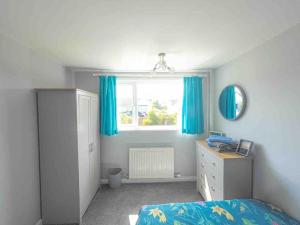 a bedroom with a bed and a window with blue curtains at Crud Yr Awel, Dinas, Pembrokeshire in Dinas