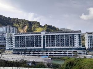 a large white building with a mountain in the background at aparthotel cameron in Brinchang