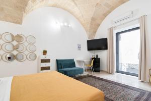 a bedroom with a bed and a chair and a tv at Kalinifta - Jacuzzi & Suites SIT in Lecce