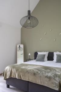 a white bedroom with a large bed and a chandelier at De Groene Bever in Lo-Reninge