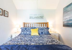 a bedroom with a blue bed with a yellow pillow at Rose Cottage in Saint Dogmaels