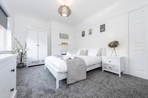 ein weißes Schlafzimmer mit einem weißen Bett und einem Spiegel in der Unterkunft Liverpool TownHouse in Liverpool