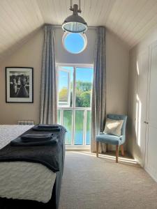 a bedroom with a bed and a chair and a window at Modern Cotswold Home w Hot Tub in South Cerney