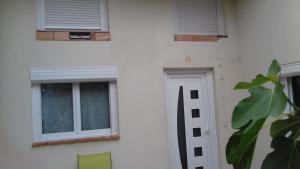 um edifício branco com duas janelas e uma porta em Maison POUR OUVRIERS seulement PAS DE TOURISME, NI FAMILLE em Stains