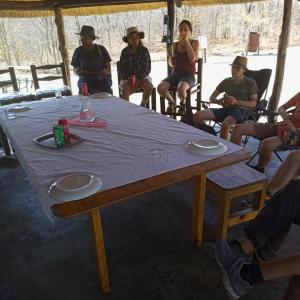 un grupo de personas sentadas alrededor de una mesa en Mokoka Rest Camp, en Nata