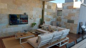 a living room with a couch and a tv on a stone wall at Ático de Lujo con Jacuzzi Climatizado en Terraza in Elche