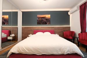 Schlafzimmer mit einem weißen Bett und roten Stühlen in der Unterkunft Pitesti Residence in Piteşti