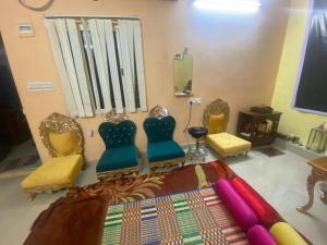 Habitación con sillas, cama y TV. en Mahavatar Babaji Farm Stay, en Bangalore