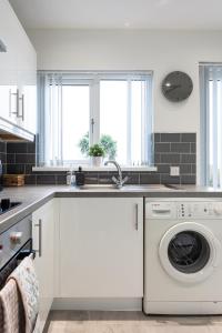 een witte keuken met een wasmachine en droger bij Fully Refurbished North Belfast Home 2 in Belfast