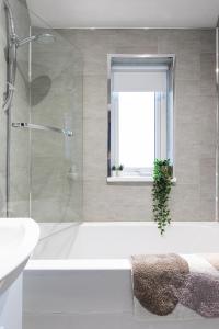 a bathroom with a tub and a window with a plant in it at Fully Refurbished North Belfast Home 2 in Belfast