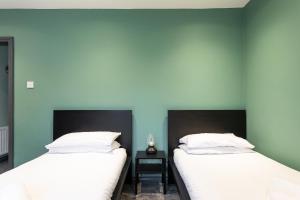 Fully Refurbished North Belfast Home 2 في بلفاست: سريرين في غرفة بجدران زرقاء