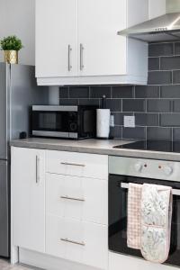 een keuken met witte kasten en een zwarte magnetron bij Fully Refurbished North Belfast Home 2 in Belfast +42 foto's