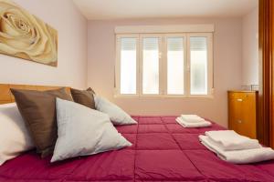 une chambre avec un grand lit avec des draps et des oreillers rouges dans l'établissement Apartamento con patio en Cádiz centro, à Cadix