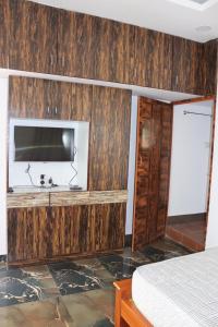 1 dormitorio con paredes revestidas de madera y TV de pantalla plana. en Royal Experience Marhaba Villa Nest, en Mahabalipuram