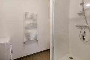 uma casa de banho branca com um chuveiro e um lavatório. em Saint-Thomas 2 - Joli T2 dans Strasbourg em Estrasburgo