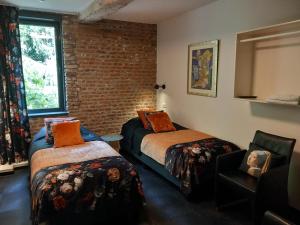 a room with two beds and a chair and a brick wall at Ruim appartement voor 14 personen in Eijsden