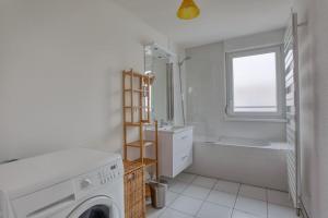 a white bathroom with a washing machine and a tub at Soultz - Bel app avec balcon dans résidence - Strasbourg in Strasbourg