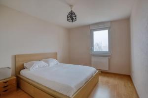 a bedroom with a white bed and a window at Soultz - Bel app avec balcon dans résidence - Strasbourg in Strasbourg