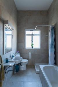 uma casa de banho com uma banheira, um WC e um lavatório. em Spacious modernist Apt with views & pool em Tal-Mejda