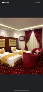 une chambre d'hôtel avec deux lits et une chaise dans l'établissement فندق أسس التاج, à Abou Arish