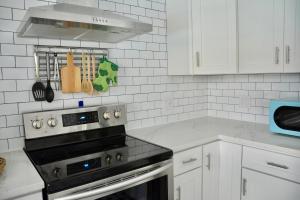 a kitchen with a stove and white cabinets at Tropical Retreat Near Beaches, Cruise Terminals in Merritt Island