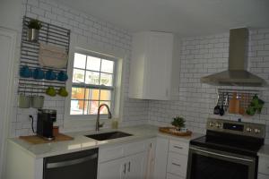 a kitchen with white cabinets and a sink and a window at Tropical Retreat Near Beaches, Cruise Terminals in Merritt Island