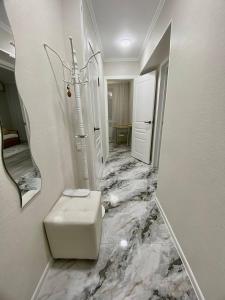 a white bathroom with a marble floor with a stool at Апартаменты аэропорт 1 in (( Turksib ))