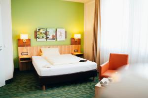 ein Hotelzimmer mit einem Bett und einem Stuhl in der Unterkunft business & conference Sporthotel Großwallstadt in Großwallstadt