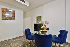 een eetkamer met een glazen tafel en blauwe stoelen bij CBD Harbour Retreat - Lovely 2BR Home in Sydney