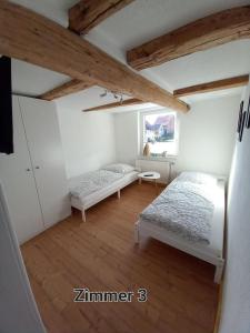 1 Schlafzimmer mit 2 Betten in einem Zimmer mit Holzböden in der Unterkunft Pension - Kleinschmidt in Urbach