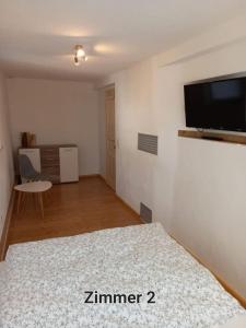 Schlafzimmer mit einem Bett und einem Flachbild-TV in der Unterkunft Pension - Kleinschmidt in Urbach