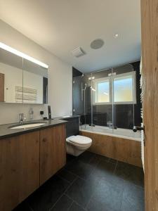 een badkamer met een toilet, een wastafel en een bad bij Luxury Apartment Davos in Davos