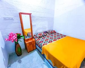 een slaapkamer met een bed en een spiegel en een vaas met bloemen bij Sahara Family Homestay in Mysore