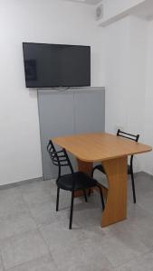 mesa de madera con 2 sillas y TV de pantalla plana. en Estudio amoblado con cama individual y baño privado en Rosario
