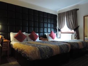 una camera d'albergo con un grande letto con cuscini rossi di Kings Park Hotel a Glasgow