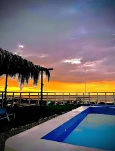 a swimming pool with a sunset in the background at La Loma de Bocapán in Bocapán