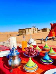 Mhamid Sahara Golden Dunes Camp - Chant Du Sable في Mhamid: طاولة عليها صحون واوعية فاكهة
