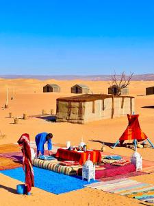 a man standing in the desert working on a blanket at Mhamid Sahara Golden Dunes Camp - Chant Du Sable in Mhamid