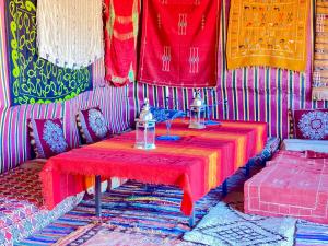 Habitación con mesa y mantel rojo. en Mhamid Sahara Golden Dunes Camp - Chant Du Sable, en Mhamid