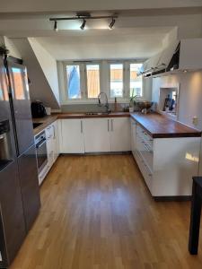 una grande cucina con armadi bianchi e pavimenti in legno di Old and charming penthouse a Oslo