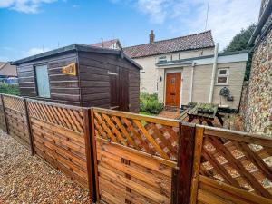 a wooden fence in front of a house at Well Furnished Holiday Cottage In The Heart Of Docking, Norfolk Ref 99009ht in Docking