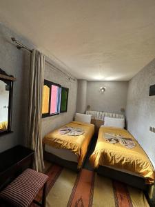 2 camas en una habitación pequeña con ventana en Dar Bargach en Tánger