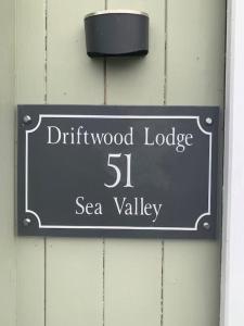 een bord op een muur dat Driftwood Lodge Sea Valley leest bij Driftwood Lodge in Bideford