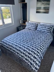 ein Bett mit einer blauen und weißen Bettdecke in einem Schlafzimmer in der Unterkunft Driftwood Lodge in Bideford