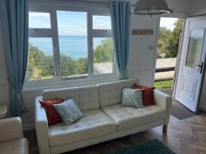 a living room with a white couch and large windows at DRIFTWOOD LODGE please note the facilities at the holiday park are seasonal March to November in Bideford