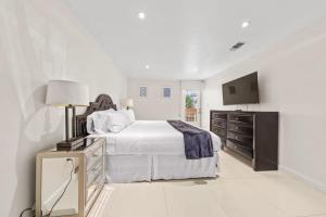 a white bedroom with a bed and a dresser and a television at Amazing BahiaMar beachfront 2 steps from amenities in South Padre Island +54 photos
