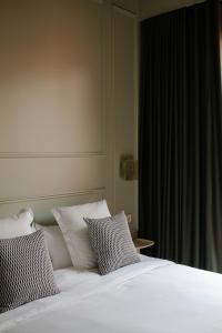 uma cama com lençóis brancos e almofadas ao lado de uma janela em La Novieta Boutique Hotel - Adults Only em Valência