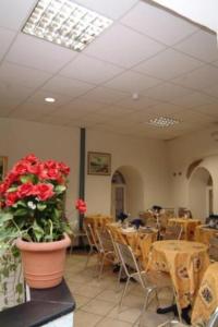 ジェノヴァにあるホテル アクアリオのテーブルと椅子、赤い花の花瓶が備わる部屋