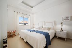 ein weißes Schlafzimmer mit einem großen Bett und einem Fenster in der Unterkunft Villa Simone in Almancil + 35 Fotos